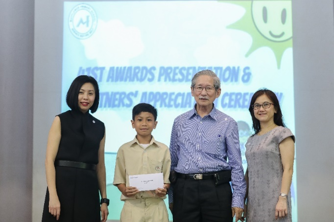 A boy holds an envelope alongside three adults at an awards presentation and partners appreciation ceremony.